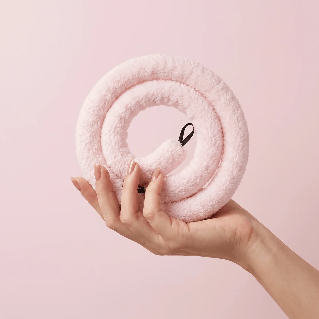 Soft pink heatless curler held in hand, gentle on all hair types for bouncy curls overnight